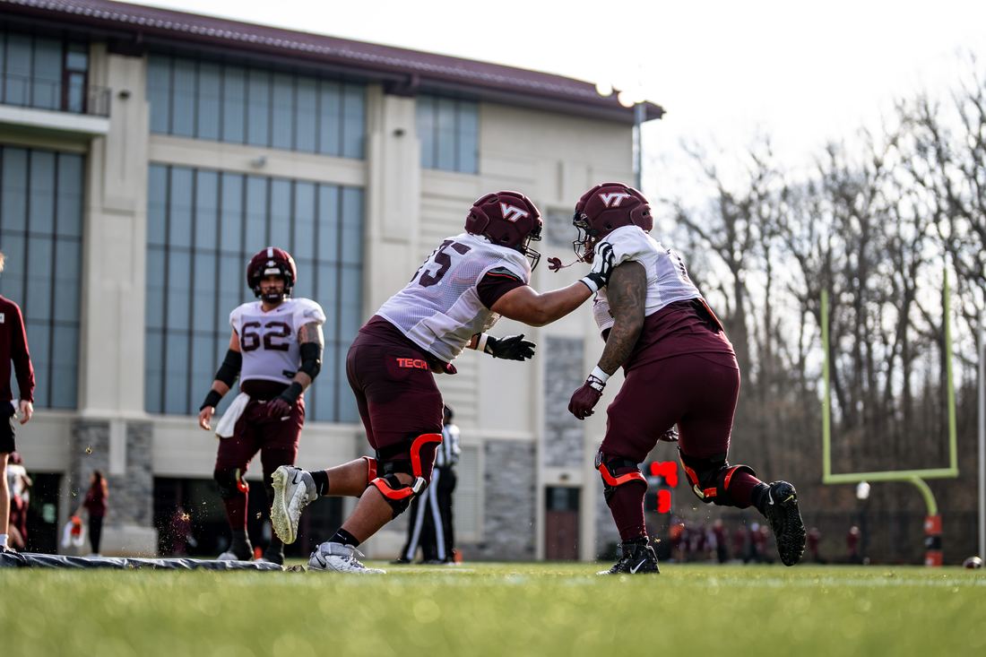 Benjamin Eziuka engaging a teammate in a one-on-one blocking drill on the Virginia Tech practice field.