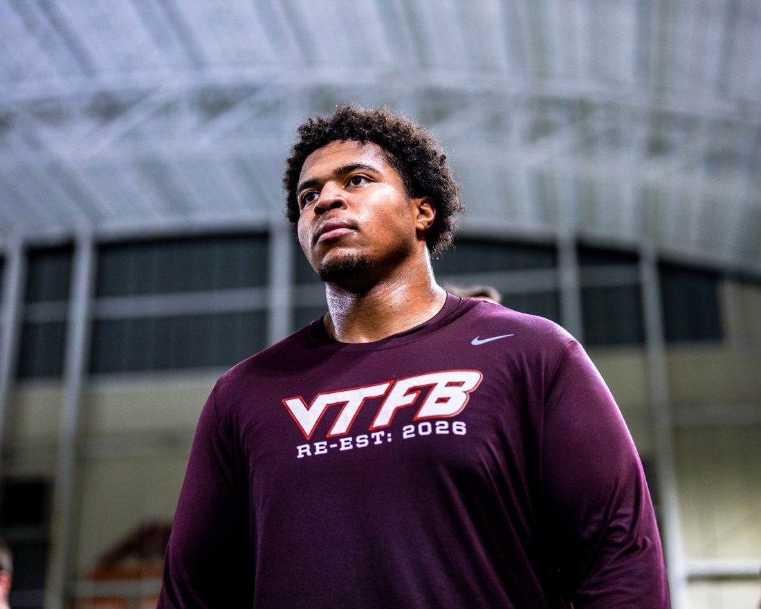 Benjamin Eziuka standing in a Virginia Tech football shirt inside the indoor practice facility, looking upfield.