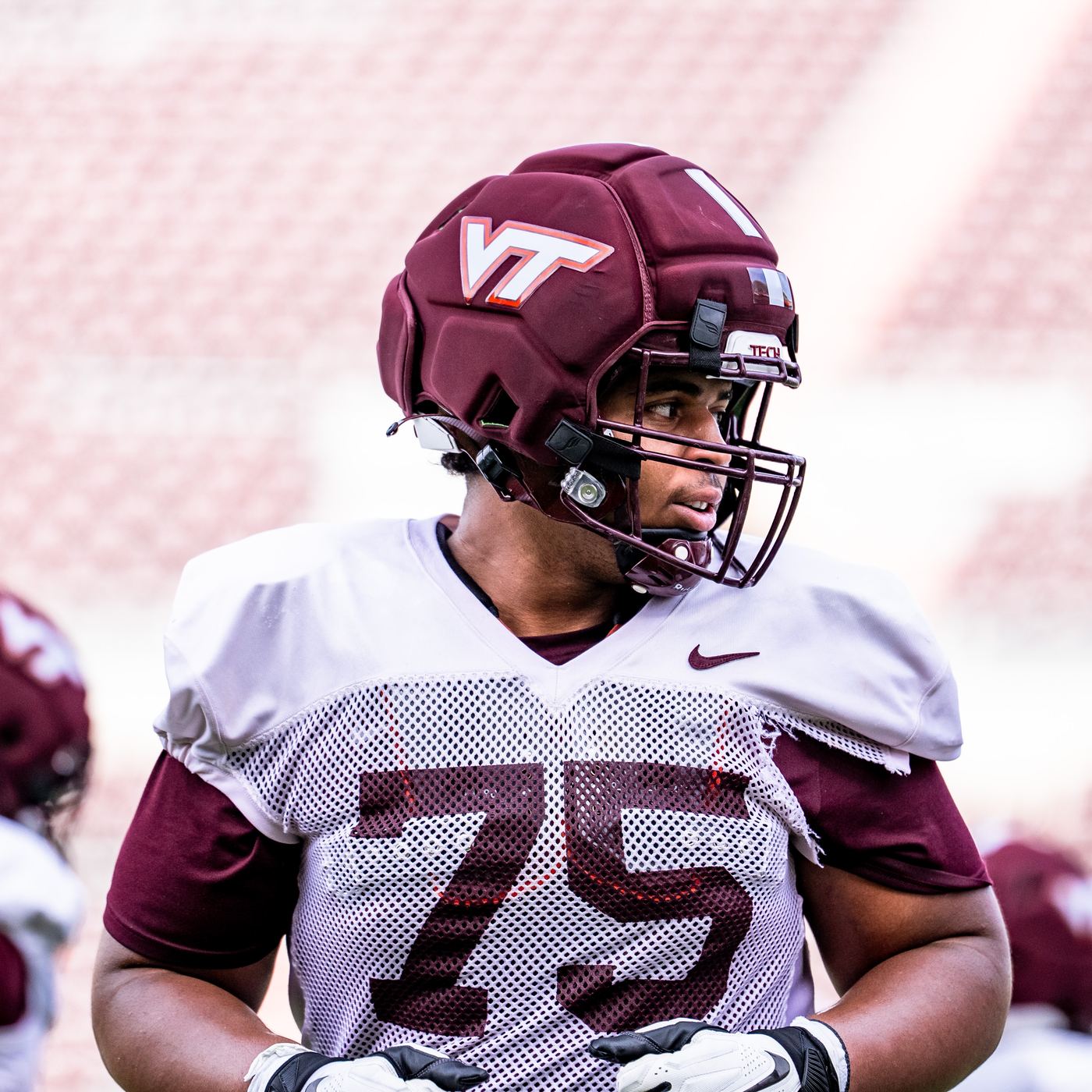 Benjamin Eziuka in a maroon Virginia Tech helmet and white number 75 practice jersey, looking off to his left.