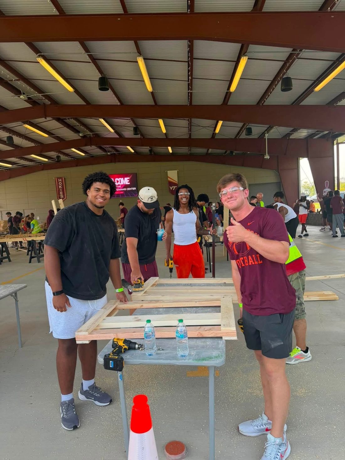 Benjamin Eziuka with Virginia Tech teammates building wooden bed frames at a Sleep in Heavenly Peace event.